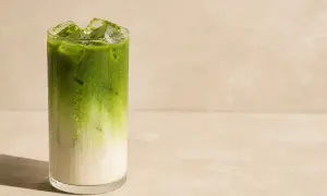 Orzeźwiająca matcha do picia z lodem w szklance, z widocznym podziałem na mleko i zielony napój.