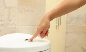 Dłoń naciska przycisk spłuczki. Szukasz domowych sposobów na zbyt częste oddawanie moczu?