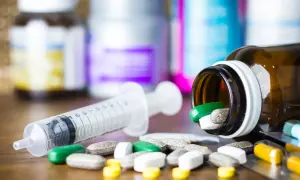 Leki, w tym zielone tabletki, rozsypane obok strzykawki. Pytanie: methocarbamol na co?