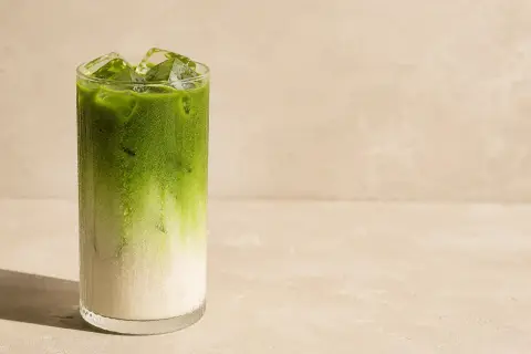 Orzeźwiająca matcha do picia z lodem w szklance, z widocznym podziałem na mleko i zielony napój.