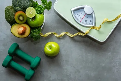 Zdrowa dieta i ćwiczenia to klucz do sukcesu w **debretin a chudnięcie**. Waga, taśma miernicza, zielone owoce i warzywa, hantle – wszystko gotowe do startu!