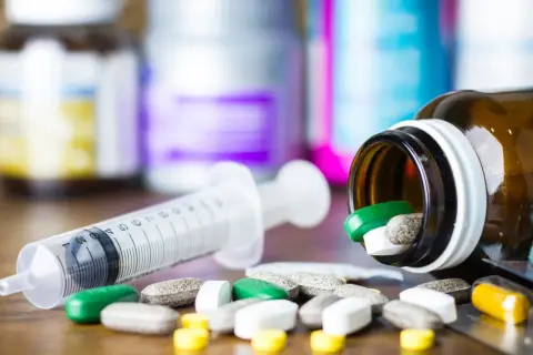 Leki, w tym zielone tabletki, rozsypane obok strzykawki. Pytanie: methocarbamol na co?