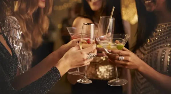 Kobiety w eleganckich strojach wznoszą toasty drinkami. Czy to czas na świętowanie, czy może na rozmowę o lekach jak metypred i alkohol?
