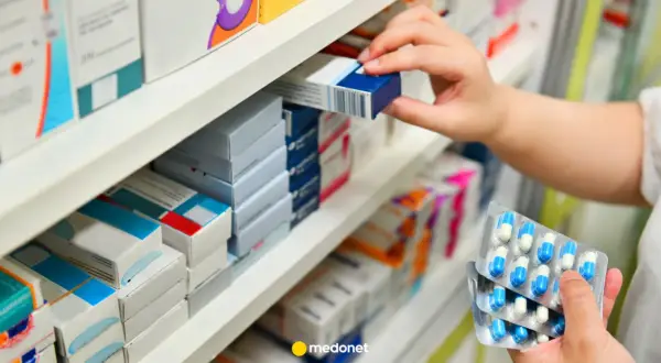 Ręka wybiera lek z półki aptecznej. W dłoni trzyma opakowanie kapsułek, które mogą być odpowiedzią na pytanie klacid na co.
