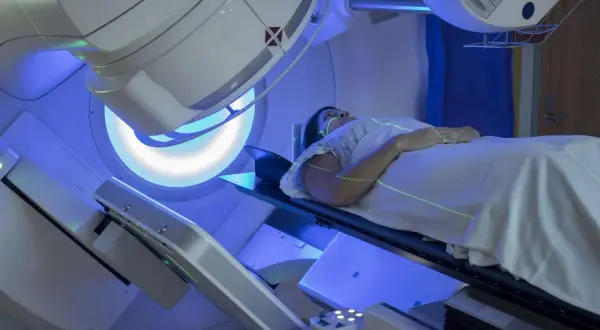 Pacjentka leży pod aparatem do radioterapii. Trudno ocenić, co gorsze chemioterapia czy radioterapia, ale obie metody leczenia raka są wyzwaniem.