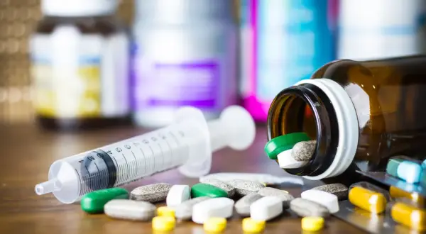 Leki, w tym zielone tabletki, rozsypane obok strzykawki. Pytanie: methocarbamol na co?