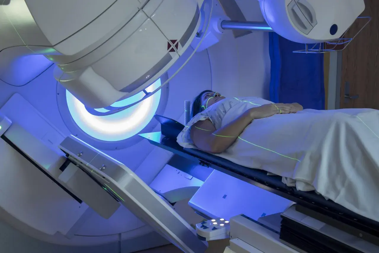 Pacjentka leży pod aparatem do radioterapii. Trudno ocenić, co gorsze chemioterapia czy radioterapia, ale obie metody leczenia raka są wyzwaniem.