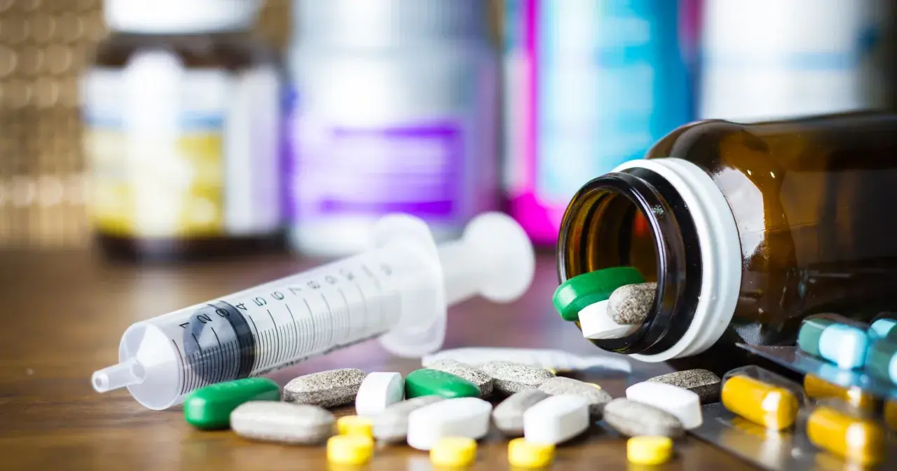 Leki, w tym zielone tabletki, rozsypane obok strzykawki. Pytanie: methocarbamol na co?