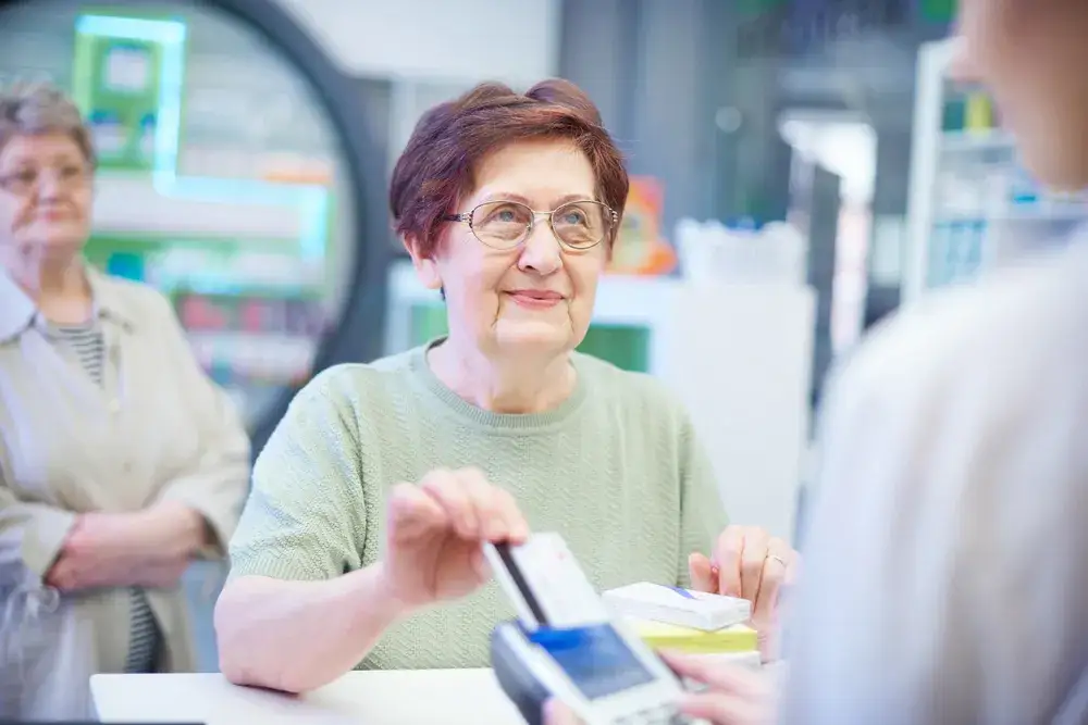 Seniorka płacąca kartą w aptece